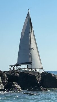 Barca a vela in difficolt&agrave; per il forte vento si allontana pericolosamente dagli scogli lungo la costa