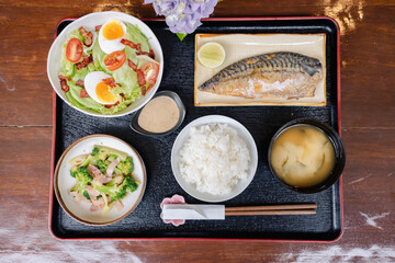 Japanese traditional meal with grilled fish rice miso soup and fresh salad on black tray representing culture style and healthy dining experience