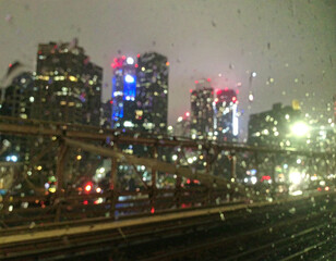Fototapeta premium Rainy Night Cityscape Viewed from a Train Blurry Lights and Skyscrapers