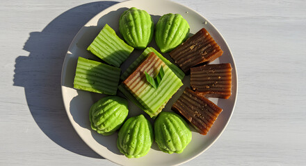 Traditional Indonesian colorful cakes including kue lapis, kue apem, and lapis legit on clean white plate