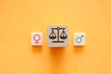 Gender equality concept with scales of justice between male and female symbols on orange...