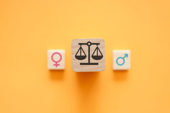 Gender equality concept with scales of justice between male and female symbols on orange background. Equal rights, workplace fairness, balance