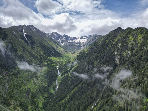 Aerial view of transfagarasan road winding through majestic mountains and lush valley, Cartisoara, Sibiu, Romania.