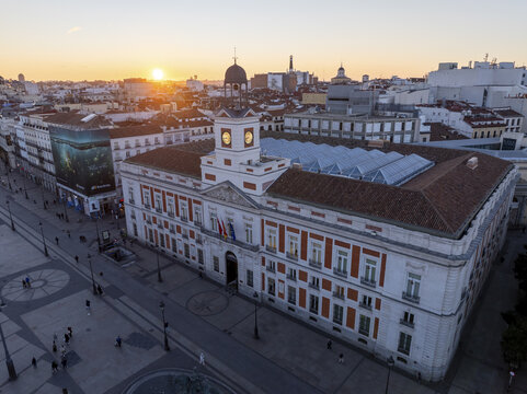 Aerial view of historic Puerta del Sol square with beautiful sunset glow and iconic clock tower, Centro, Madrid, Spain.