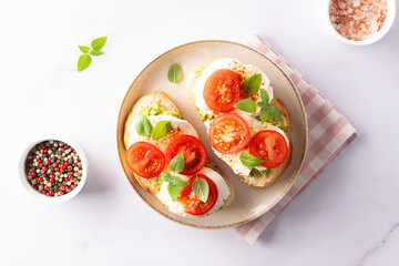 Fresh homemade caprese sandwich with avocado paste, mozzarella cheese, cherry tomatoes, fresh aromatic basil leaves and spicy hot oil top view. Healthy homemade food concept.