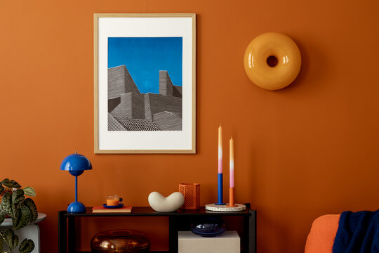 Stylish living space with orange wall, architectural mock up artwork, blue lamp and contemporary accessories.