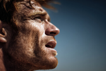 Fototapeta premium profile portrait of man with his mouth open taking deep breath under intense sunlight