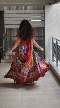 Woman twirling in vibrant mirror work chaniya choli, showcasing traditional Gujarati attire for Navratri and Garba celebrations, highlighting colorful ethnic fashion and cultural heritage.