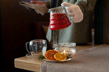 Pouring Hot Berry Drink with Dried Citrus and Candle