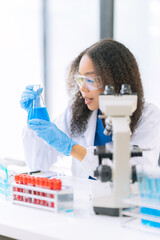 Fototapeta premium An African American female scientist is conducting clinical laboratory experiments with a microscope and performing laboratory analysis of stem cell research.