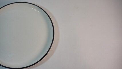 A simple, elegant round plate with a sleek black rim, perfect for showcasing delicious dishes in a minimalist setting. Ideal for food photography and tableware collections.