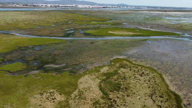 Ria Formosa with riverbed exposed at low tide and Olhao in the background on Algarve in Portugal