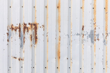 Weathered corrugated metal wall with peeling paint and light rust 
