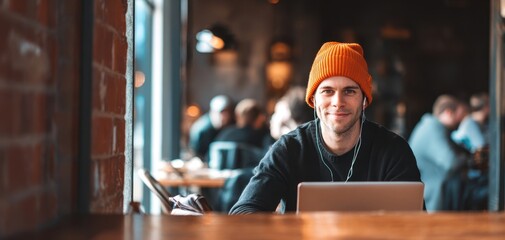 The young man in a beanie working on his laptop in a cafe