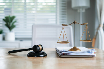 A wooden gavel rests on a stack of documents beside a laptop, symbolizing power and justice.