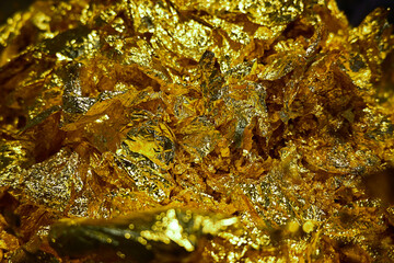 Crinkled gold foil sheets shimmer with layered texture and brilliance.