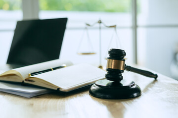 A wooden gavel rests on a stack of documents beside a laptop, symbolizing power and justice.