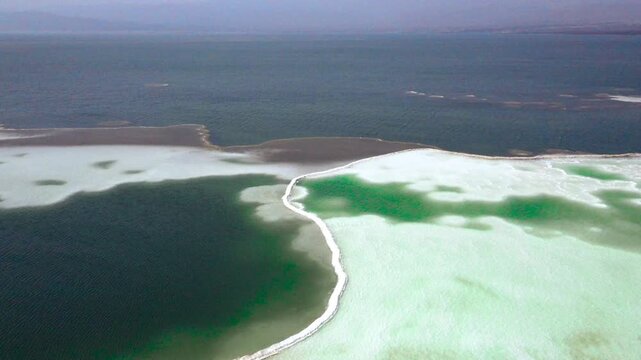 Drone view of Lake Assal's shimmering turquoise water meeting white salt flats in Djibouti