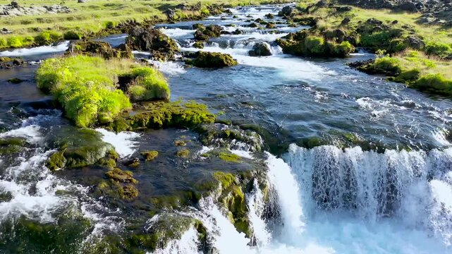 Drone view of Faxi Waterfall in Iceland, where glacial waters spill over a broad rocky ledge