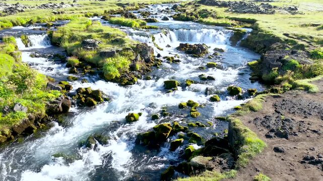 Drone view of Powerful glacial waters plunge over the wide rocky ledge of Faxi Waterfall
