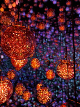  Close-up of vibrant orange glowing spheres in a dark immersive art installation, with reflections creating an infinite visual effect. Inspired by the style of teamLab exhibitions.