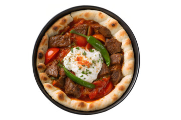 Overhead view of a g&uuml;ve&ccedil; dish with meat, tomatoes, peppers, and yogurt in a black pan