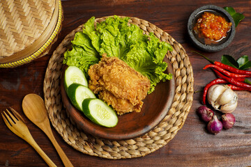Crispy Fried Chicken with Fresh Vegetables and Chili Sambal on Rustic Wooden Table
