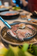 Sizzling hot Mookata, Thai BBQ grill pork on circle hot pan. Fresh, marinated pork and vegetables grilled on hot plate. A delicious and smoky dish, perfect for sharing with friends and family.