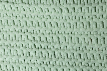 A close-up view of soft green fabric featuring a complex woven pattern. The texture adds depth,...