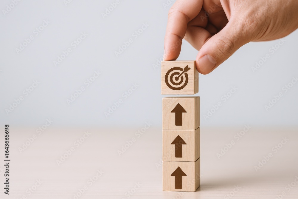 Poster achieving goals: hand placing target block atop arrow blocks to symbolize success and direction