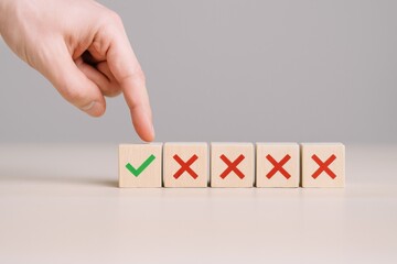 Choice Selection: Hand Choosing Correct Option Marked with Green Tick, Rejecting Red Crosses on Wooden Blocks