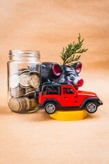 Glass jar filled with coins with a yellow lid and a red truck with a coin-saving and growth piggy...