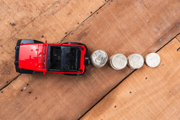 Glass jar filled with coins with a yellow lid and a red truck with a coin-saving and growth piggy...