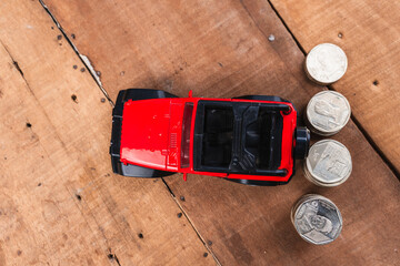 Glass jar filled with coins with a yellow lid and a red truck with a coin-saving and growth piggy...