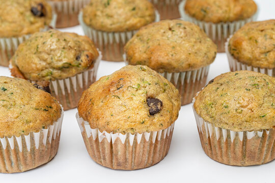 Rows of Fresh Baked Zucchini and Chocolate Chip Muffins on a White Background