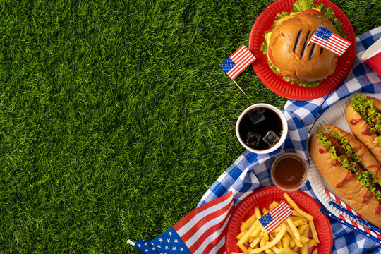 Labor Day and Independence Day celebration with American food, including hamburgers, hot dogs, fries, and flags, on a picnic setting representing patriotism - Powered by Adobe