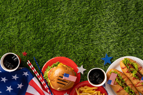 Labor Day and Independence Day celebration idea featuring delicious American-style food on the grass in a picnic setting, including hamburgers, hot dogs, fries, and patriotic decorations - Powered by Adobe