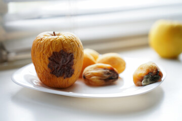 rotten fruits on a light background, apricot and apple