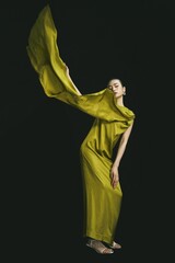 Elegant female model in flowing green dress with dramatic fabric movement.