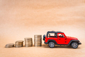 Glass jar filled with coins with a yellow lid and a red truck with a coin-saving and growth piggy...