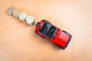 Glass jar filled with coins with a yellow lid and a red truck with a coin-saving and growth piggy...