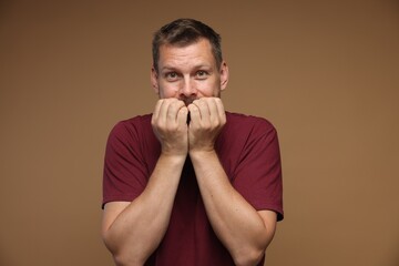 Man suffering from panic attack on brown background