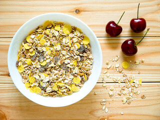A Bowl of muesli breakfast with spilled muesli and cherries