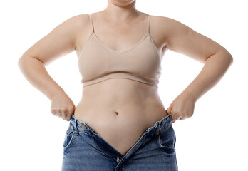 Liposuction. Woman trying to put on tight jeans against white background, closeup