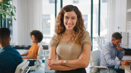 Fototapeta premium Portrait Of Young Smiling Businesswoman Working On Laptop At Desk In Office