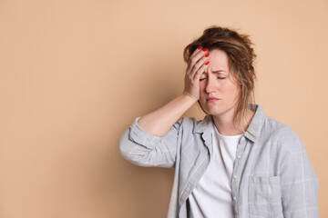 Woman suffering from hangover on beige background. Space for text