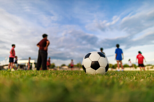 Action sport outdoors of kids having fun playing soccer football for exercise in community rural area under the twilight sunset sky. Picture with copy space.