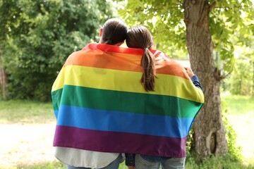 LGBT concept. Women with rainbow flag outdoors, back view