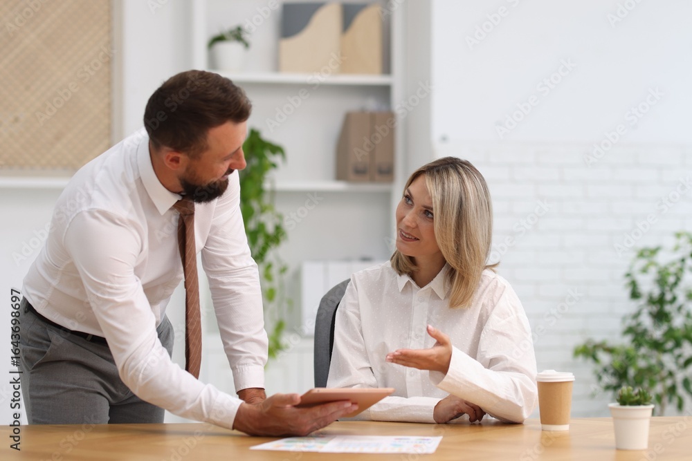 Poster smiling business partners working with tablet at table in office