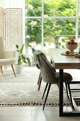 Wooden table, chairs, armchair and decor in dining room. Interior design